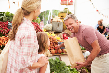 Family Buying Fresh Vegetables At Farmers Market Stall