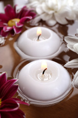 Fototapeta na wymiar Bowl of spa water with flowers and candles, closeup