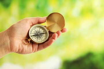 Female hand with compass on bright blurred background