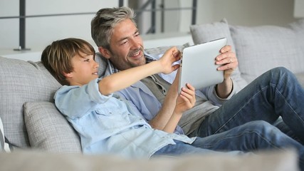 Daddy and son websurfing on digital tablet at home - Powered by Adobe
