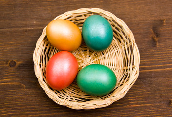 Fototapeta na wymiar Basket with colored eggs on wooden table top view