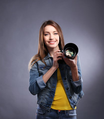 Obraz premium Young female photographer taking photos on grey background