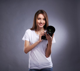 Fototapeta premium Young female photographer taking photos on grey background