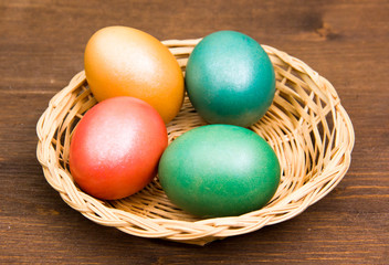 Fototapeta na wymiar Basket with colored eggs on wooden table