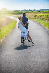 A newlywed couple is taking the road on a bike.