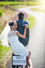 A newlywed couple is taking the road on a bike.
