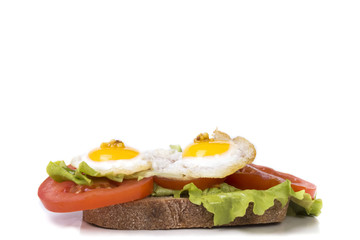 fried eggs with a little tomato and lettuce on a piece of fresh