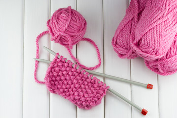 Group of pink woolen yarn and knitting needles 