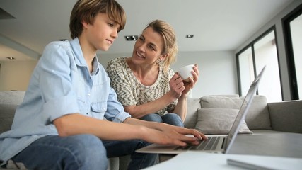Mother looking after son doing homework on laptop - Powered by Adobe