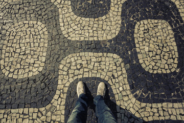 Light Sneakers shoes walking on Ipanema Beach mosaic sidewalk top view, Rio de Janeiro