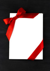 White sheet of paper decorated red bow and ribbon