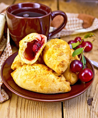 Pies with cherry and mug on board