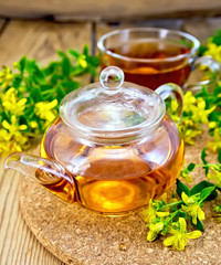 Tea from tutsan in glass teapot and cup on board