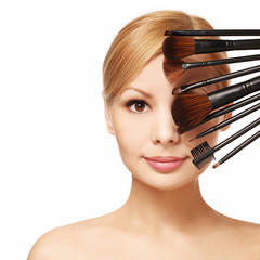 Beautiful woman with makeup brushes near attractive face