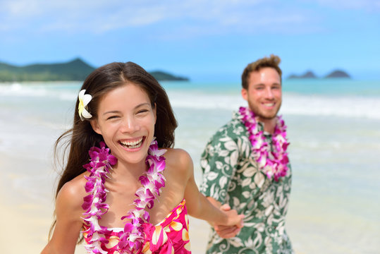 Happy Hawaii beach holiday couple in Hawaiian leis