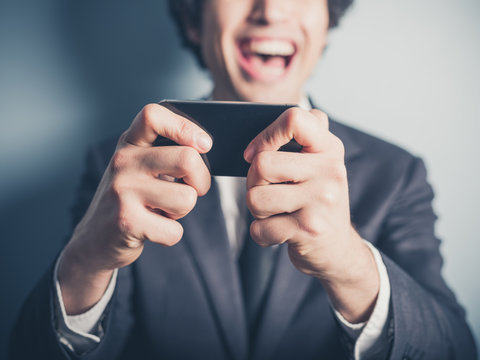 Happy businessman laughing at his smartphone