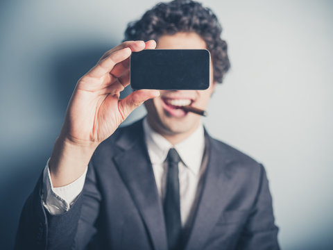 Young businessman smoking cigar and taking a selfie
