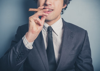 Young businessman smoking a cigar