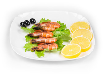 Raw shrimps on plate with lettuce and lemon.