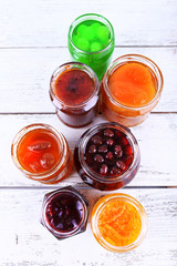Homemade jars of fruits jam on color wooden planks background