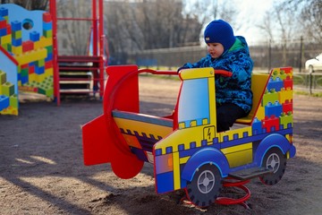 Fototapeta na wymiar The little boy at a playground plays on the children's machine
