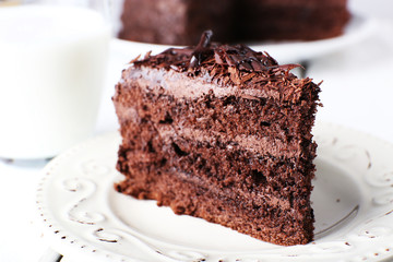 Sliced tasty chocolate cake in plate on wooden table, closeup
