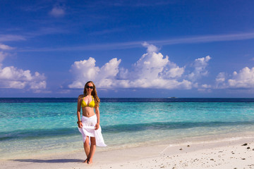Beautiful girl in white skirt and yellow top on the beach overlo - obrazy, fototapety, plakaty