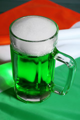 Glass of green beer on Ireland flag background