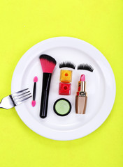 Makeup accessories on plate on colorful background