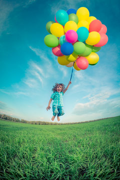 Child with toy balloons in spring field