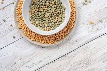 Two bowls with yellow and green peas on wooden white background