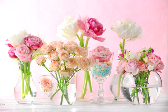 Beautiful spring flowers in glass vases on light pink