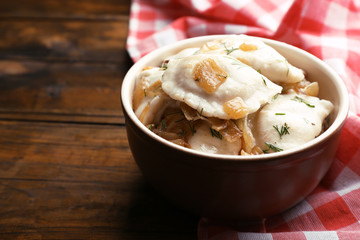 Tasty dumplings with fried onion in brown bowl,