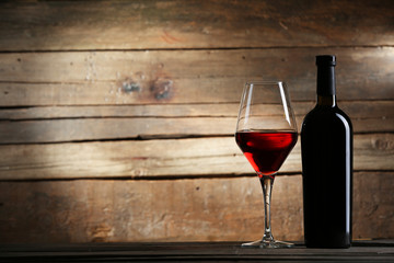 Wine bottle with glass on wooden background