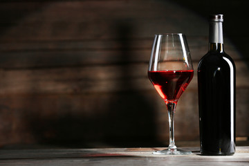 Wine bottle with glass on wooden background