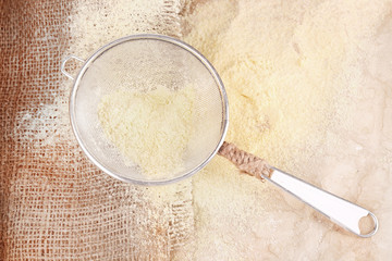 Flour with sieve on burlap cloth, closeup