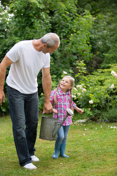 Mädchen und Vater mit Zinkgießkanne im Garten