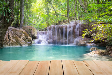 Waterfall, green forest in Erawan National Park in Thailand montage with wooden floor. Landscape with water flow, tree, river, stream and rock at outdoor. Beautiful scenery of nature for vacation.