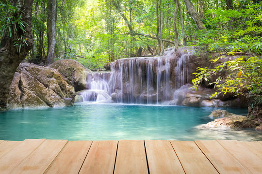 Waterfall, green forest in Erawan National Park in Thailand montage with wooden floor. Landscape with water flow, tree, river, stream and rock at outdoor. Beautiful scenery of nature for vacation. © DifferR