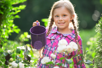 Mädchen im Garten gießt Blumen