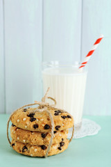 Tasty cookies and glass of milk on color wooden background