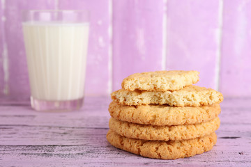Tasty cookies and glass of milk on color wooden background