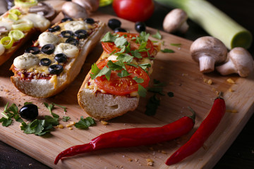 Different sandwiches with vegetables and cheese on cutting board on table close up