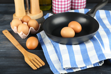 Still life with eggs and pan on wooden background