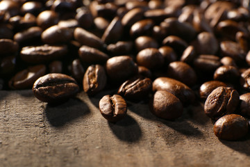 Pile of coffee beans on wooden table, closeup