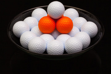 Black ceramic bowl full of golf balls