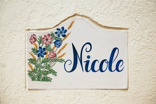 Nicole - old tile on city street wall with flower and beautiful