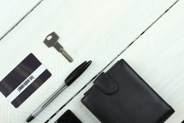 Men's wallet, phone, keys and card on wooden table