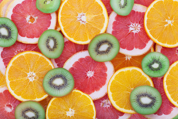 Fototapeta na wymiar Orange, kiwi and grapefruit rings as background