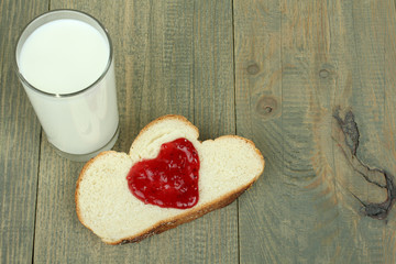 Bread with  jam and glass of milk on wooden table